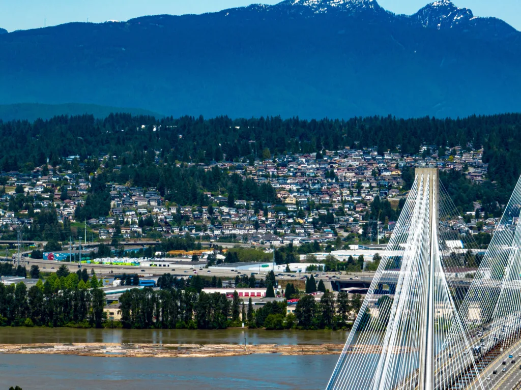 A drone shot of Coquitlam cityscape with Port Mann Bridge, river and mountain in the background