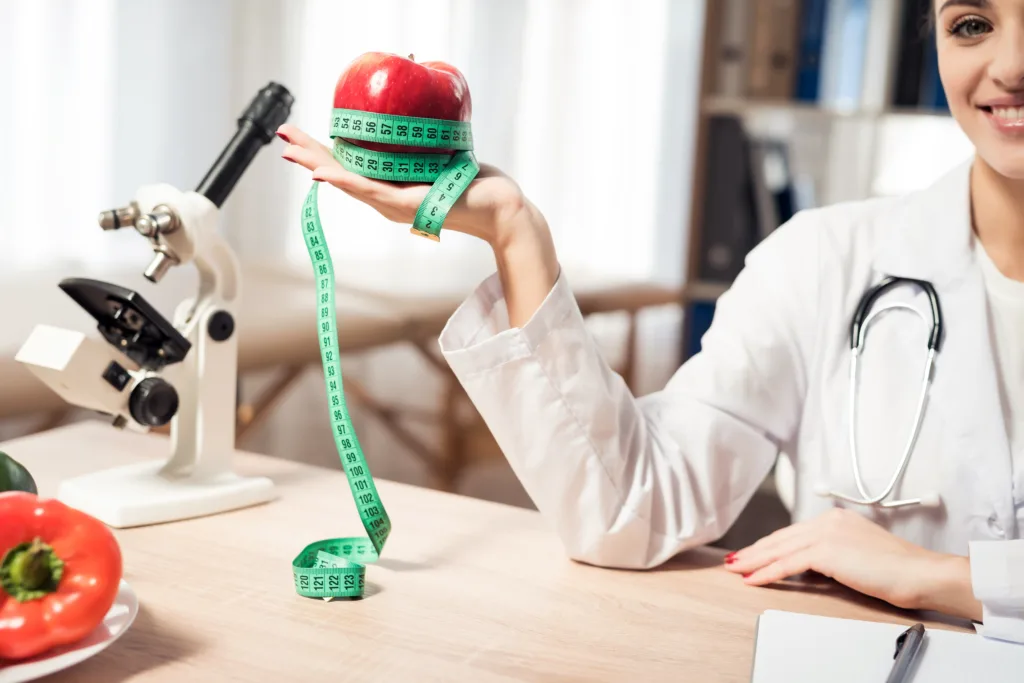 Coquitlam dietician holding a red apple with a measuring tape 