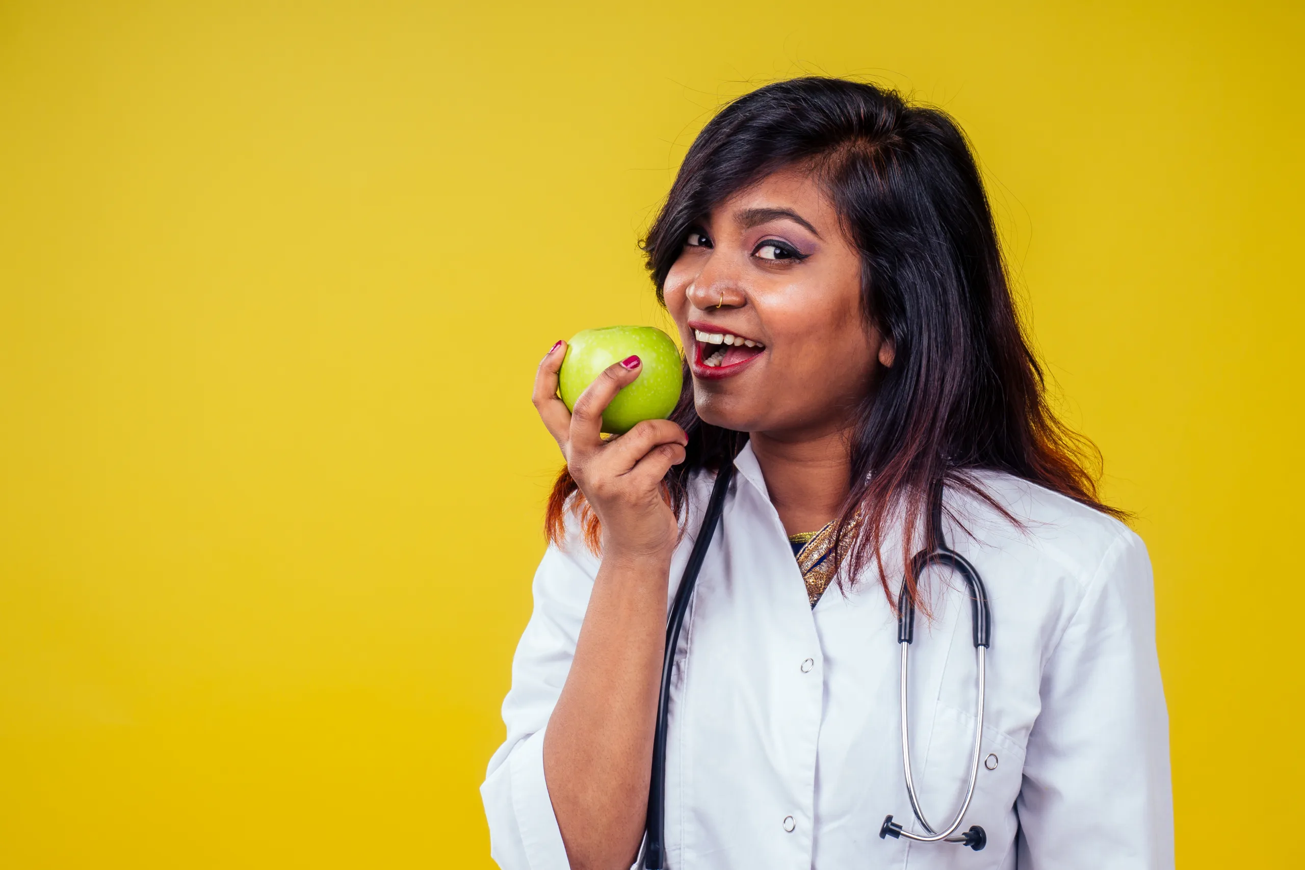 dietician from surrey eating apple with lab coat