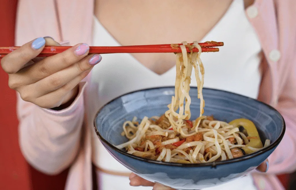asian noodle bowl eaten by a lady with chopsticks 