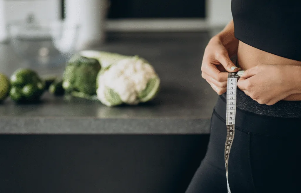 lady measuring waist with tape measure in the kitchen