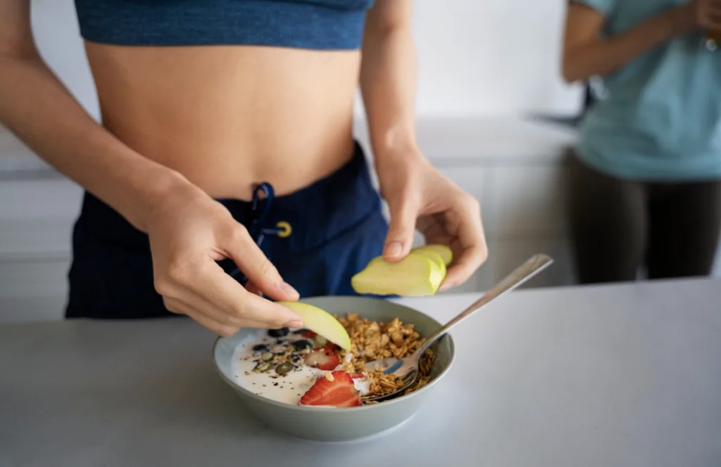 Healthy breakfast bowl with yogurt, granola, berries, seeds, and apple slices, showing a simple high-fiber food choice for weight loss