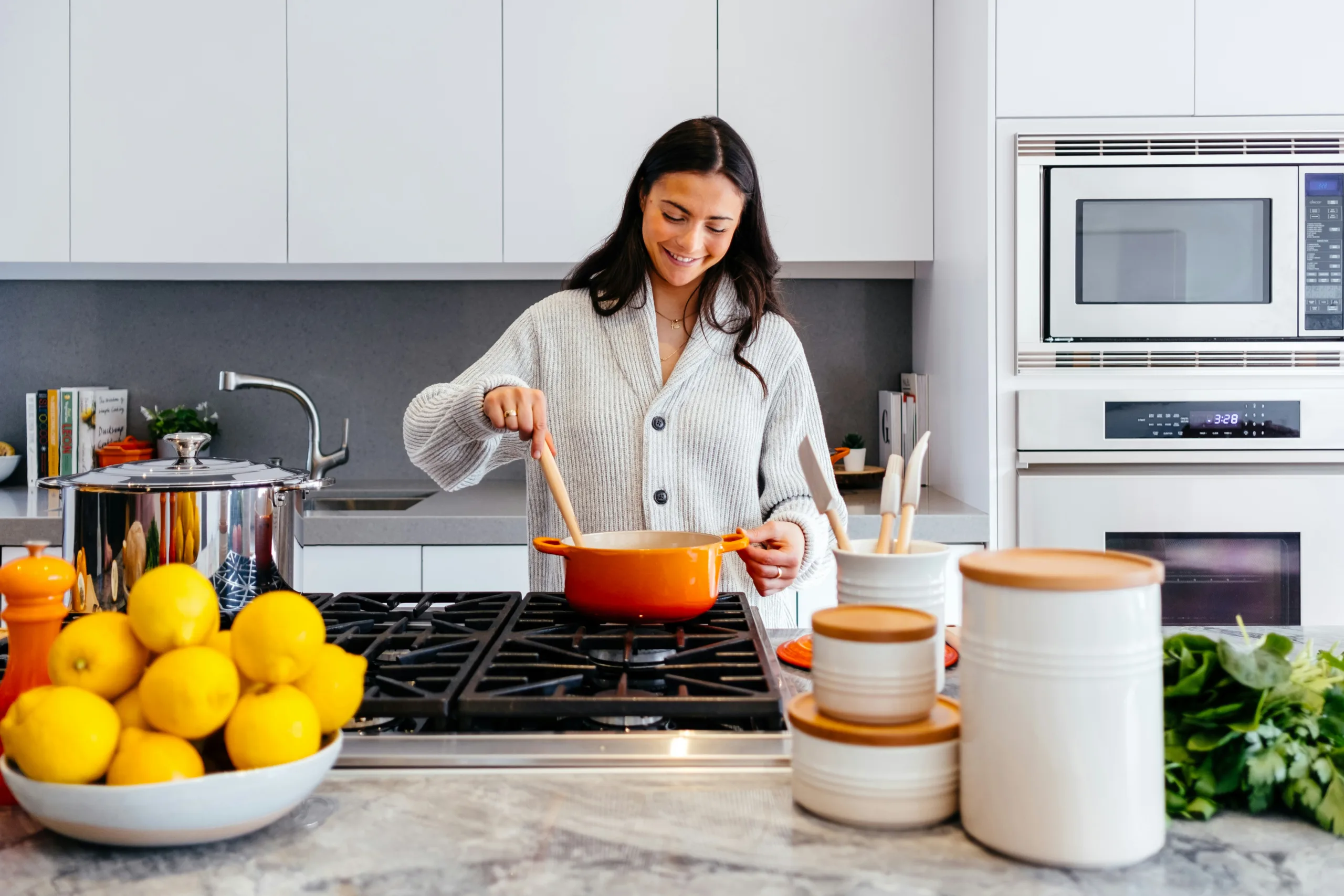 Woman stirring an orange pot on a kitchen stove