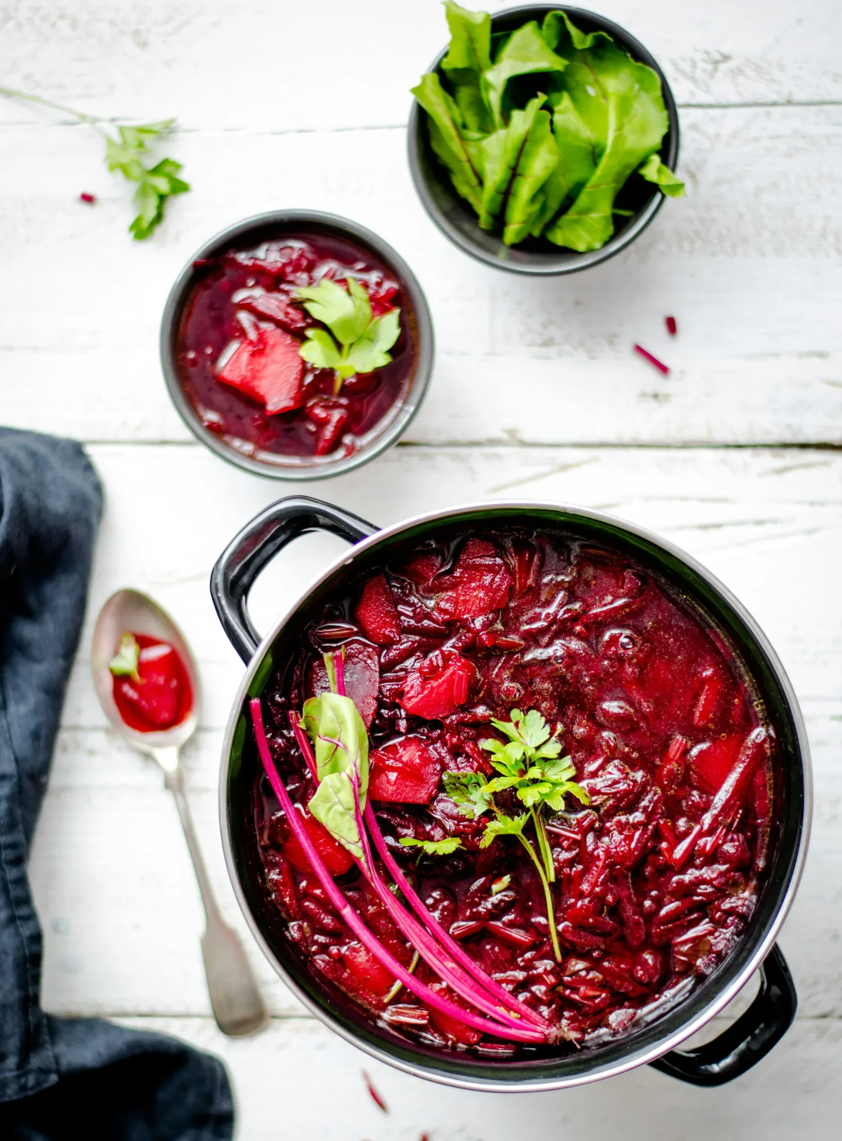 Pot and bowl of beetroot soup on a white wooden table